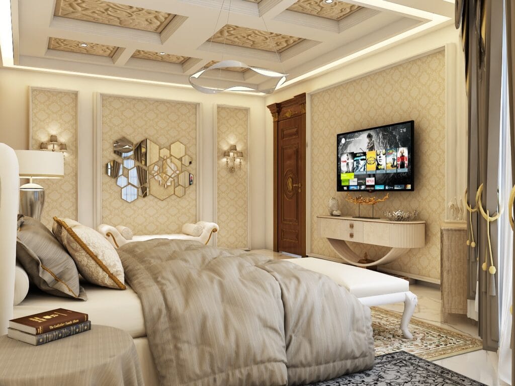Elegant bedroom with gold accents, cozy bedding, and a wall-mounted TV.