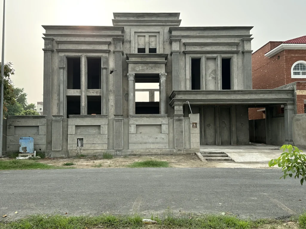 A grey concrete house under construction with classical architectural elements.